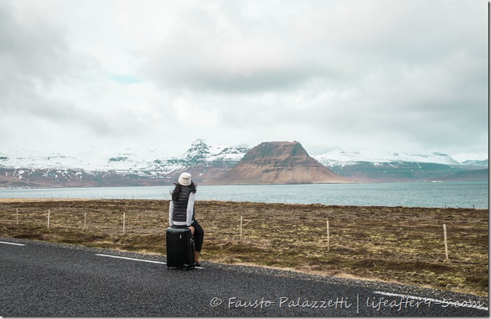 Woman sitting on luggage looking at the stunning view of Snæfellsnes Peninsula